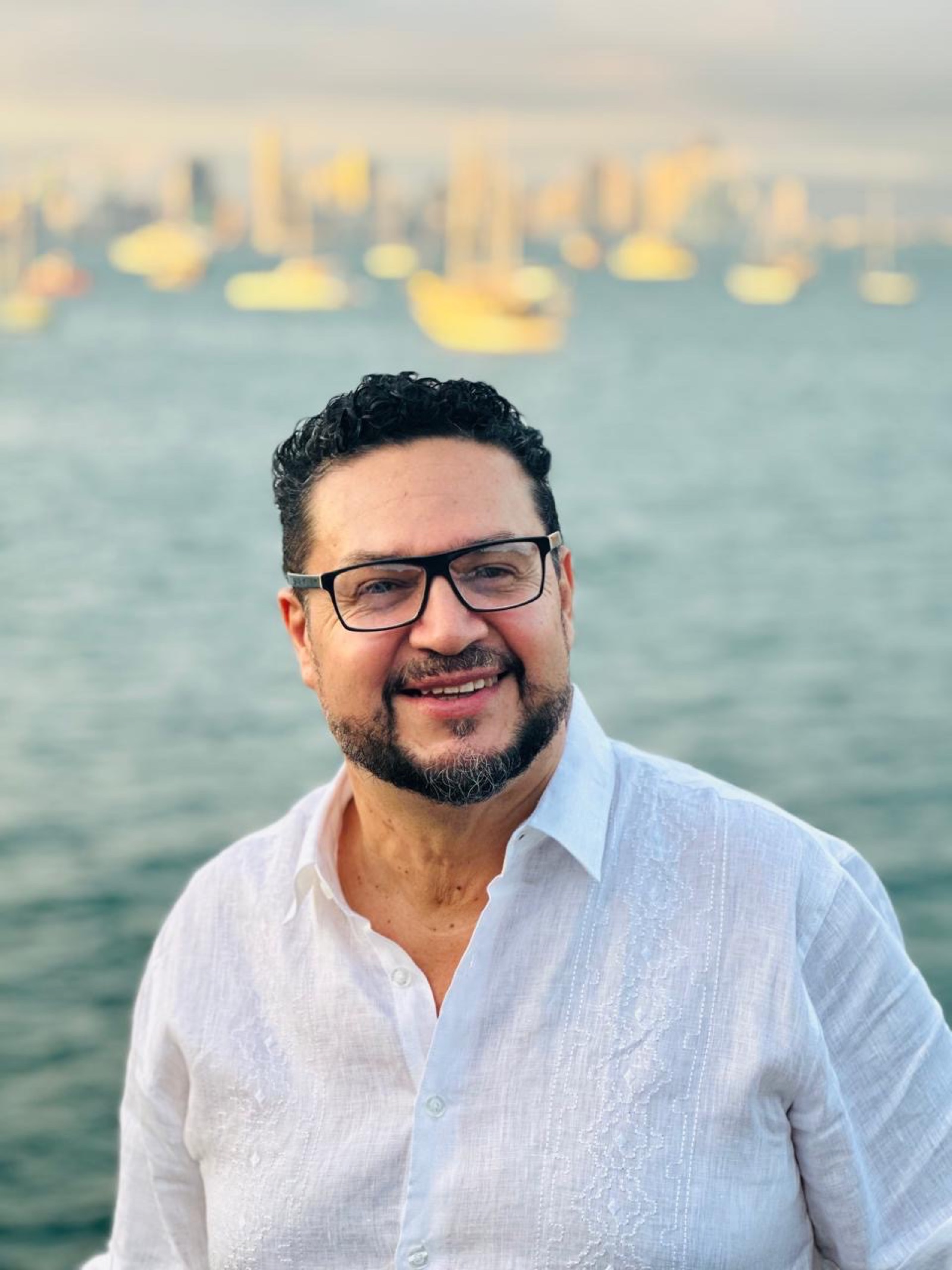 Javier Orias sonriendo en un muelle frente al mar